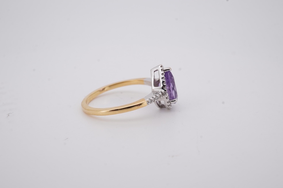 A modern 18ct gold and single stone pear cut amethyst set ring, with diamond chip set border and shoulders, size O, gross weight 3.4 grams. Condition - fair to good